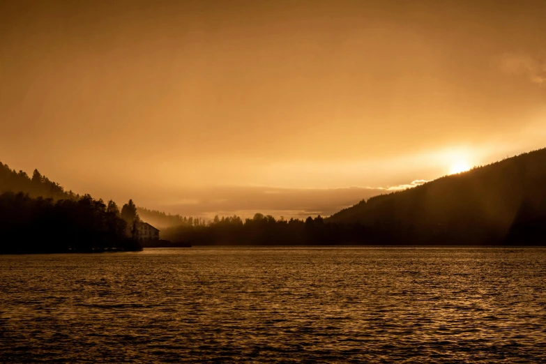 the sun is setting on a mountain over a lake