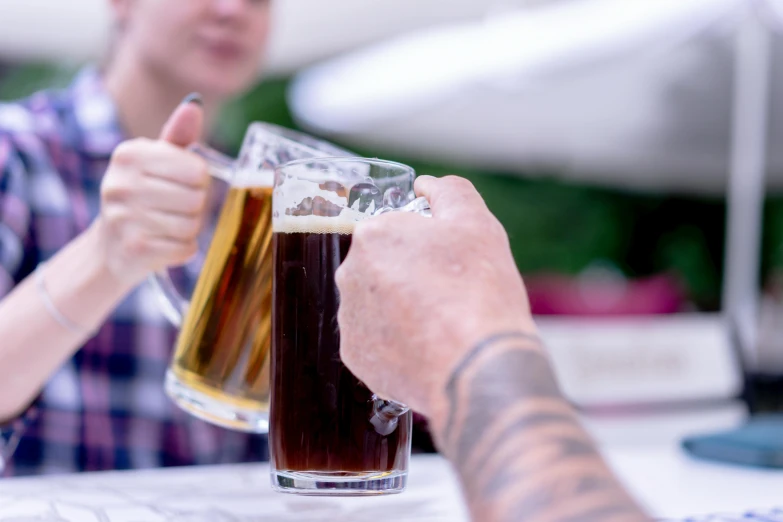 two people hold a beer at a table