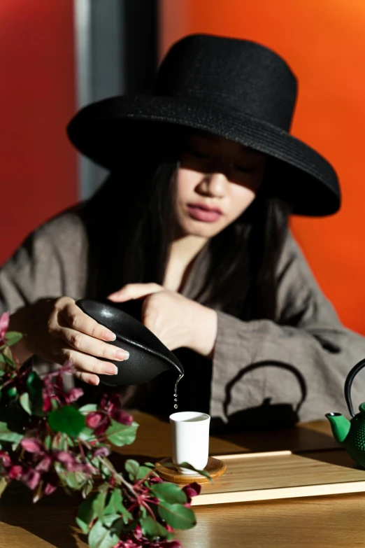 a woman wearing a black hat and pouring water