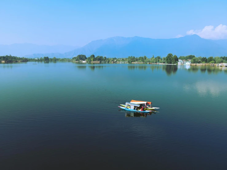 a small boat floating on top of a lake surrounded by mountains