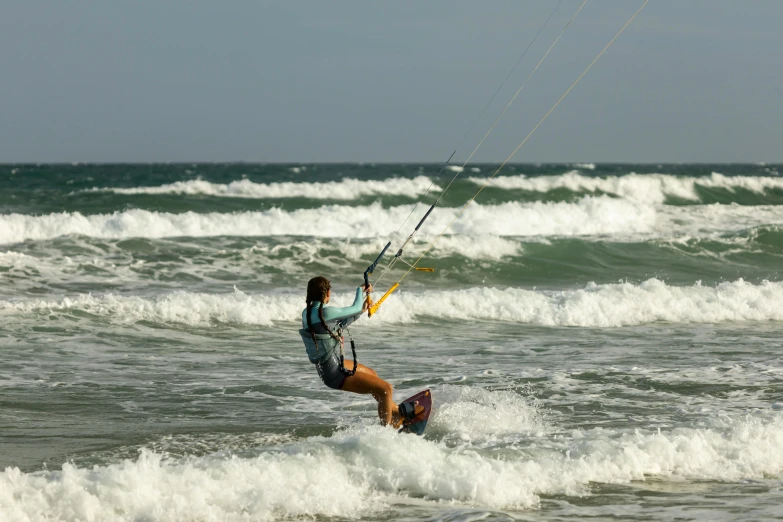 a woman on skis holds onto a rope with a big wave