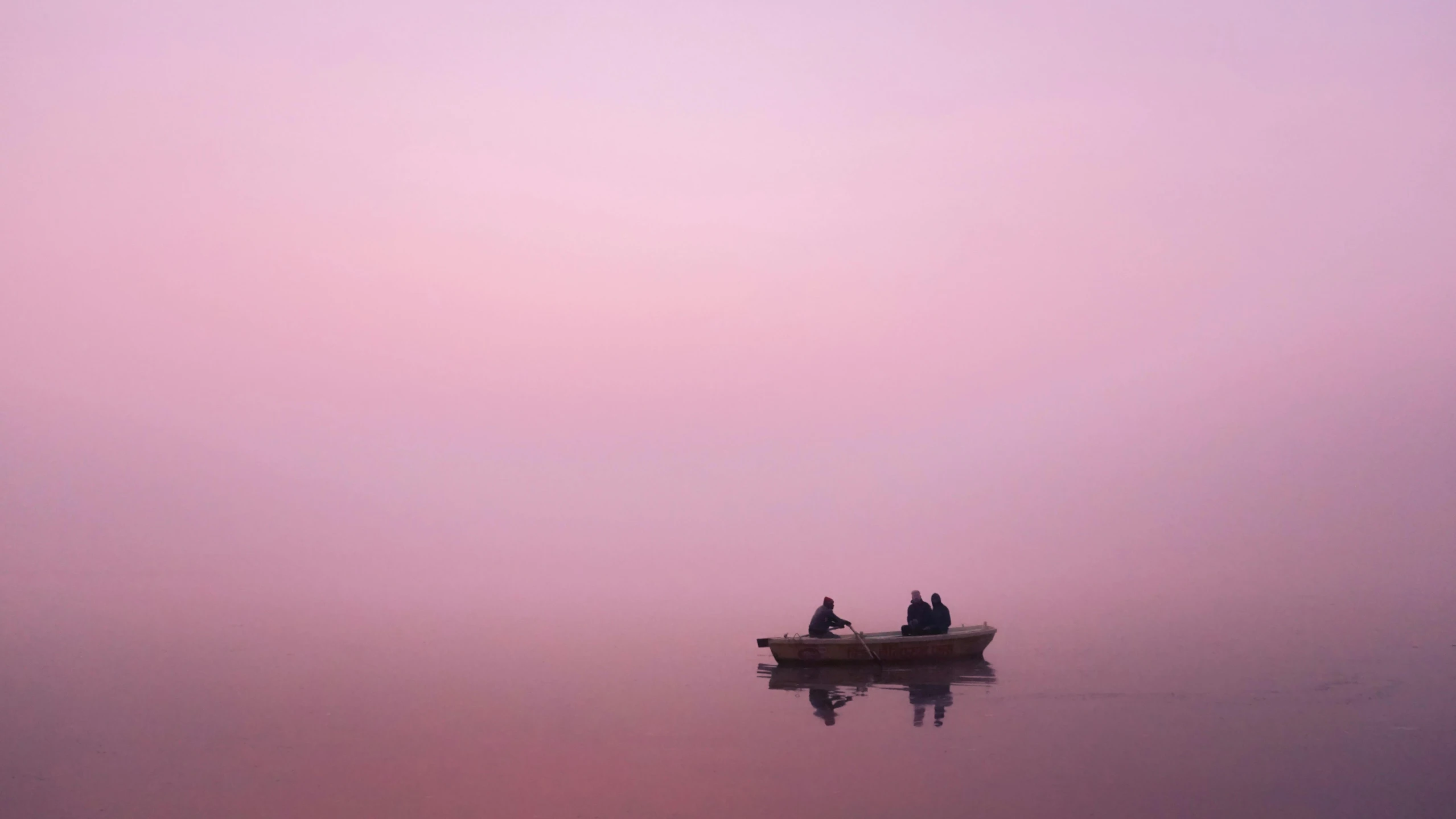 three people in a small boat on a misty river