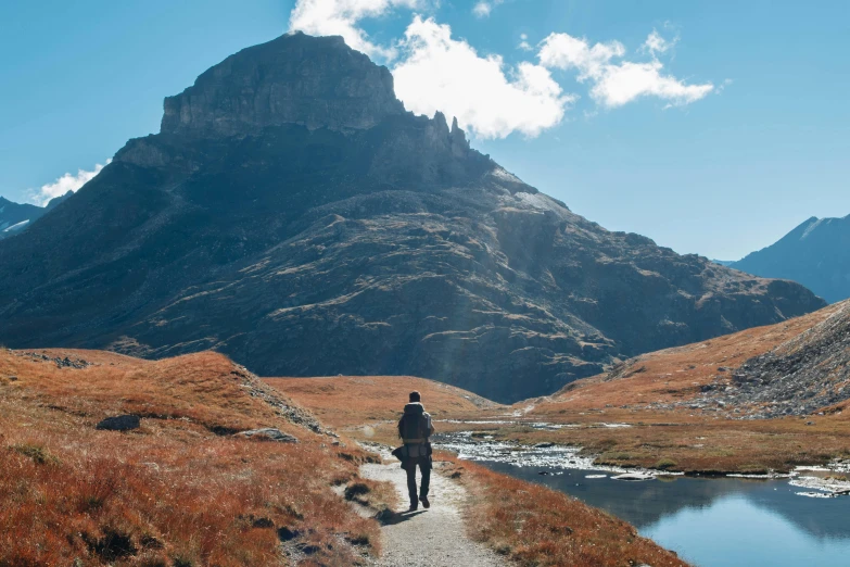 a person is walking away from the camera on a path in the mountains