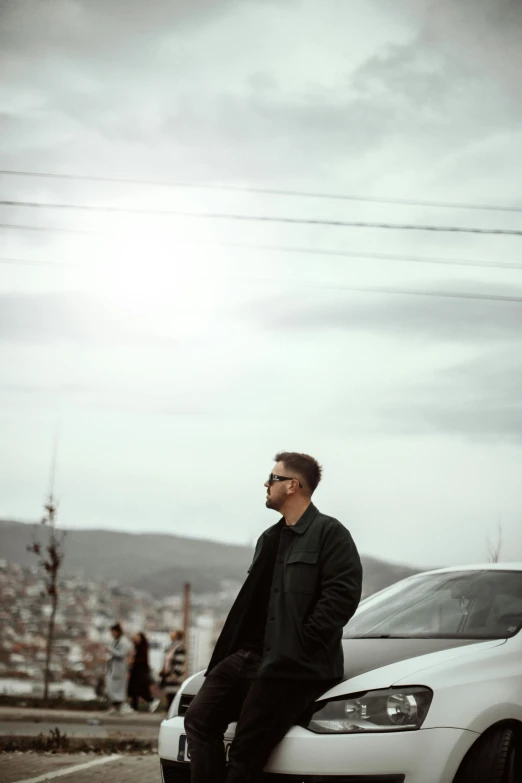 a man leaning on the back of a parked car