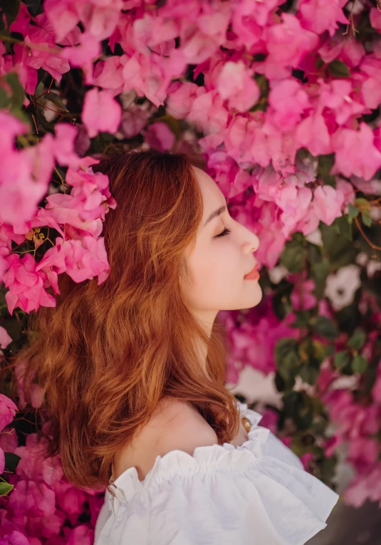 red - haired woman standing in pink flowers