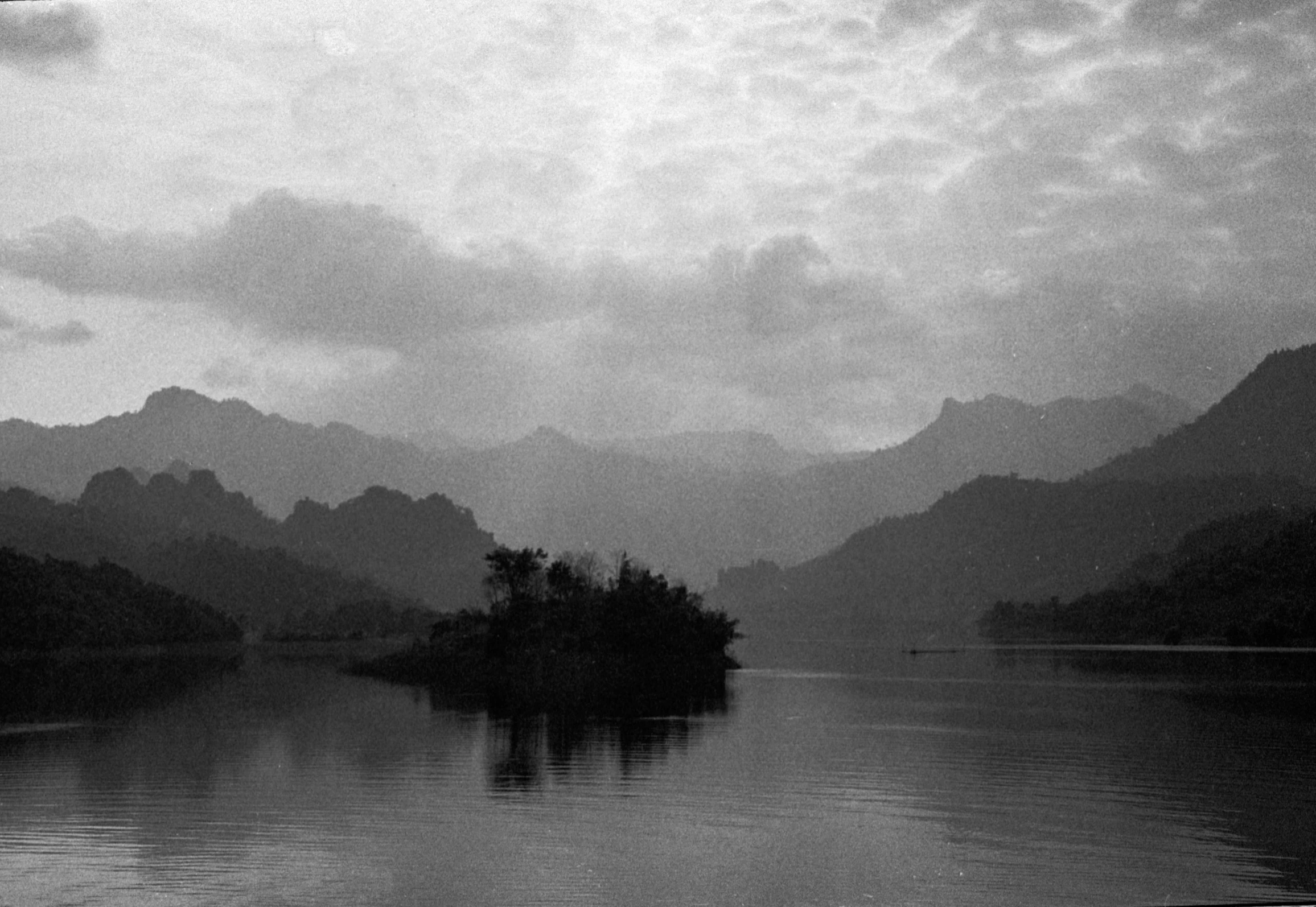 an island in a lake with a small boat sailing past