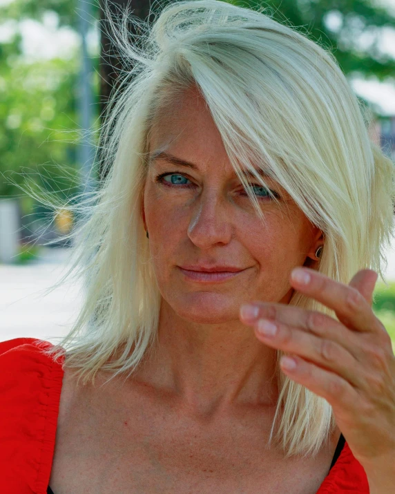 an older blond woman is holding her chin near her chin