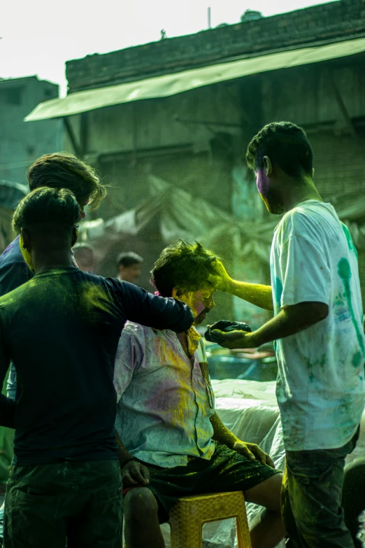 a man is getting his hair cut by other people