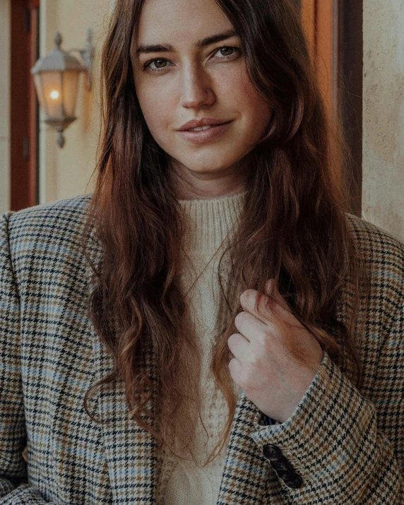 a woman with long hair is leaning against a wall