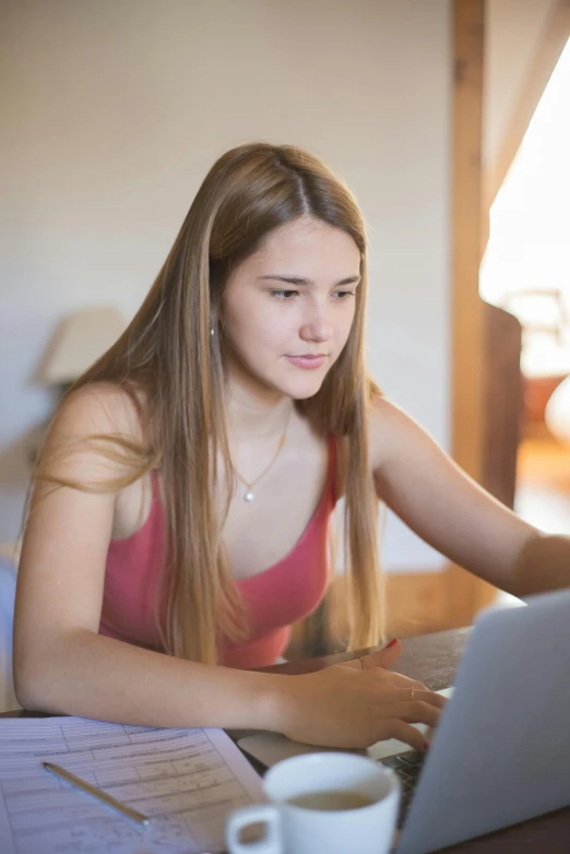 young lady at table typing on laptop computer