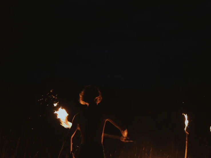 woman standing in front of a fire show with her arms spread wide