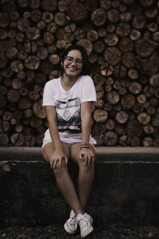 a young woman sitting on the edge of a pile of wood