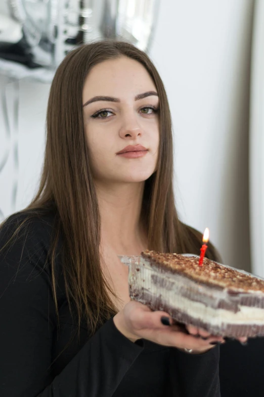 a woman holding up a piece of cake with a candle