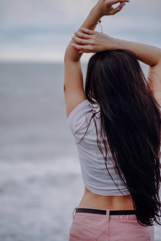 a woman with her arms raised in front of the ocean