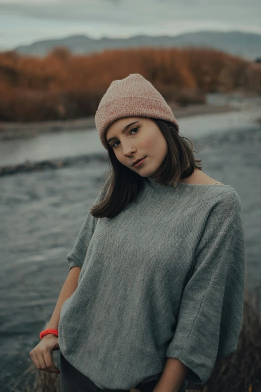 the woman is posing for the picture next to a river