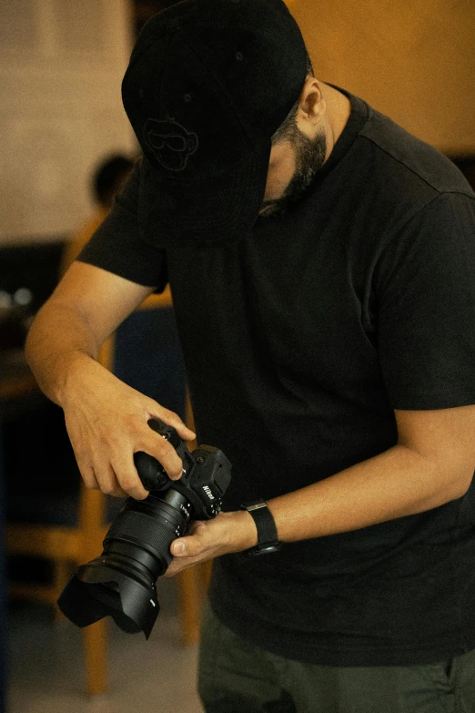 a man in a black mask holding a camera and wearing a black wrist strap