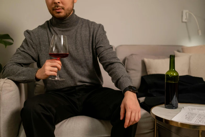 a man is sitting down holding a glass of wine