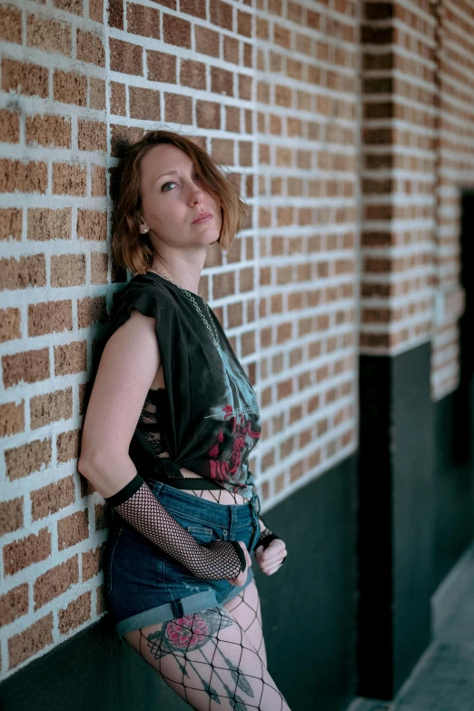 woman leaning against a brick wall