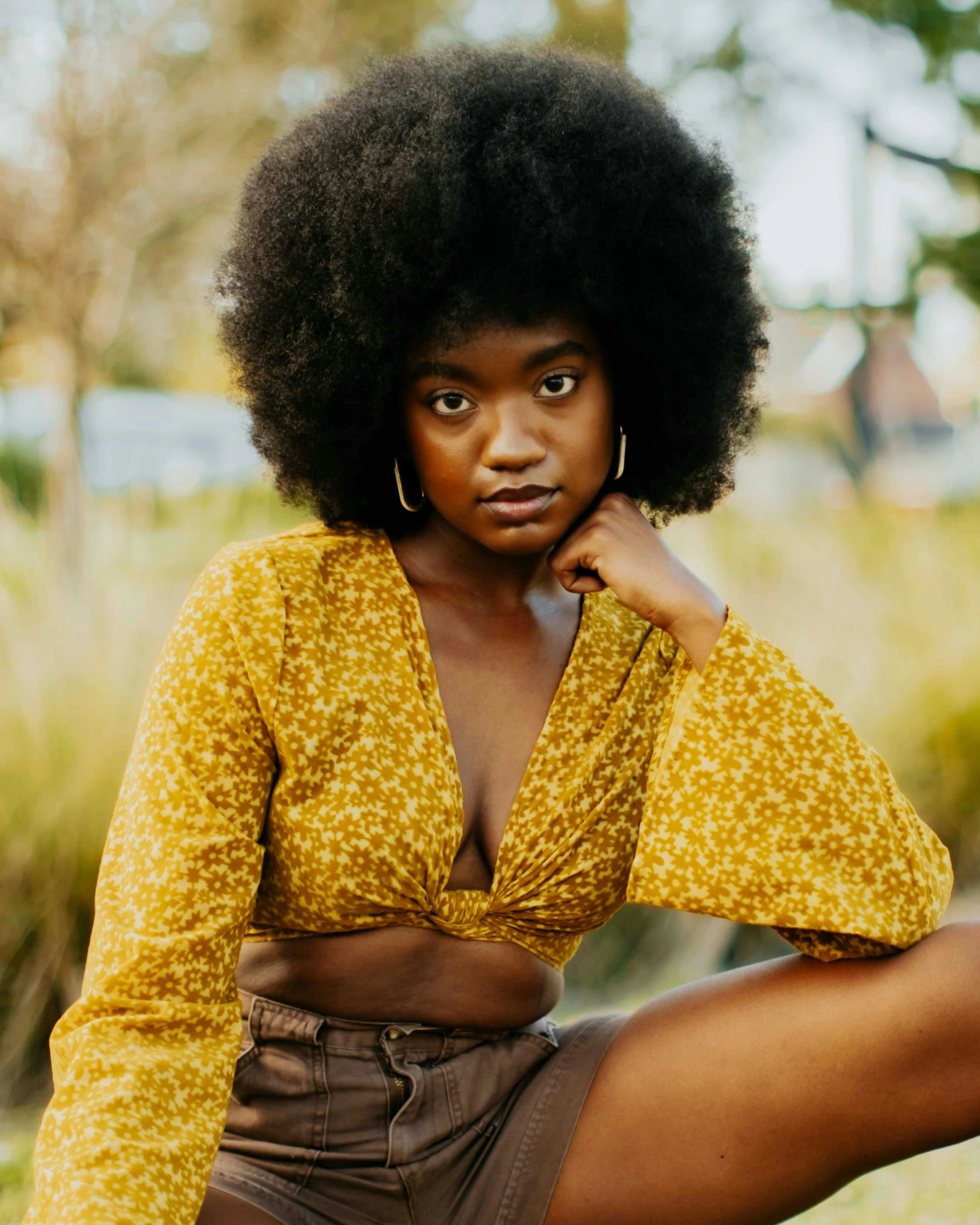 a black woman with very large afro sitting on the ground