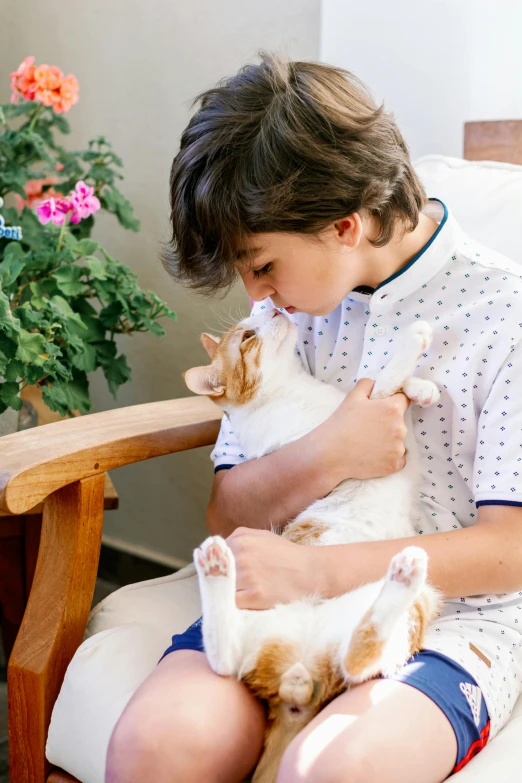 a boy in pajamas holding a cat on his lap