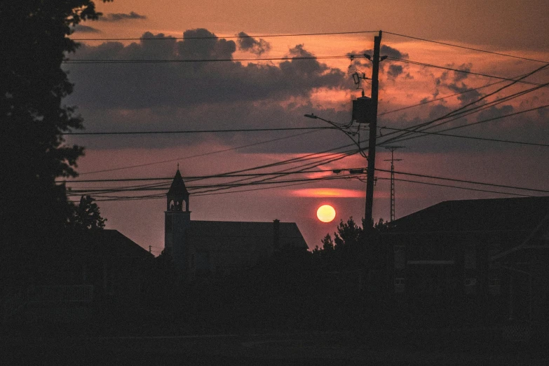 a sunset behind power lines and wires above a city