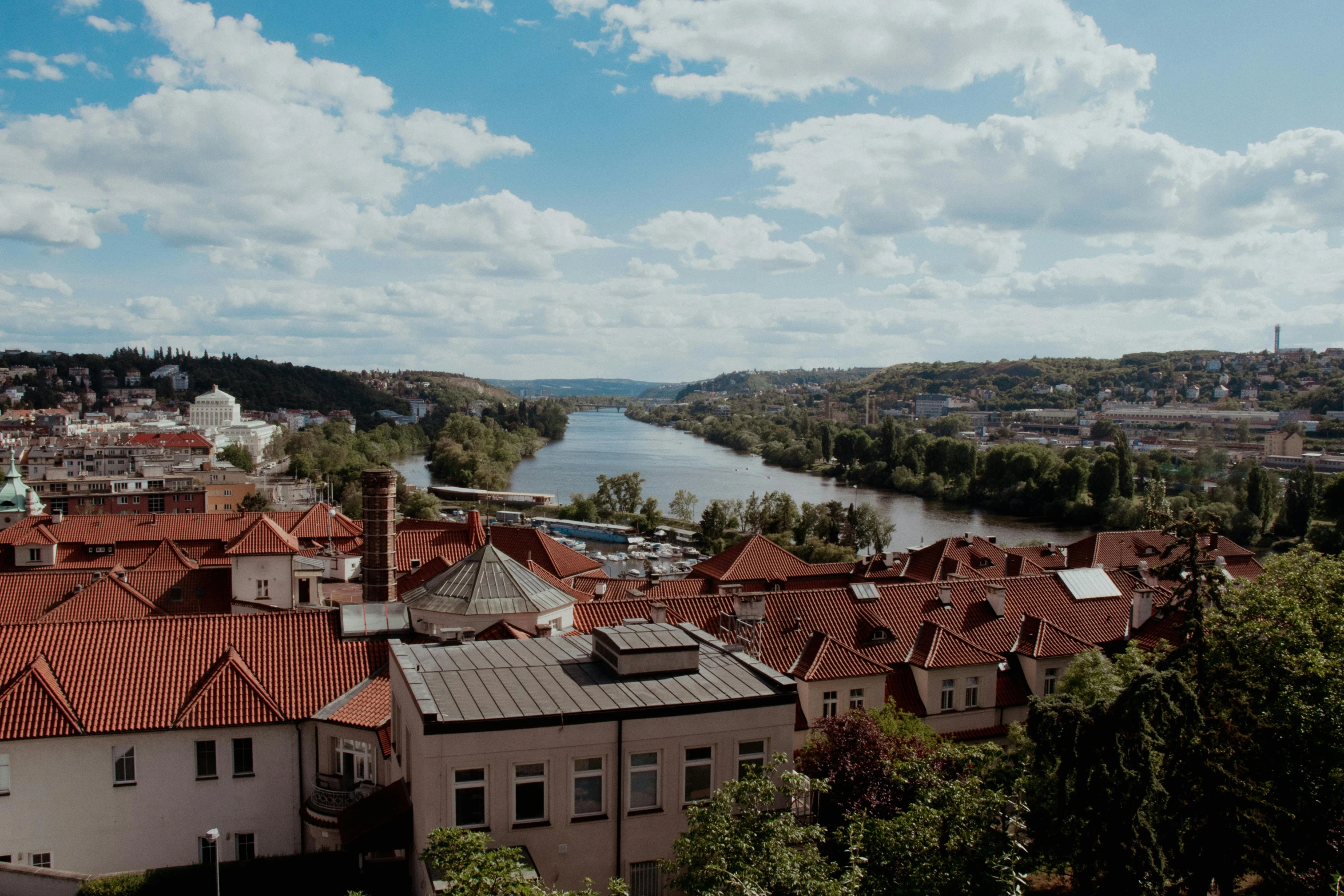 the view of a city with red roofs from a height of trees