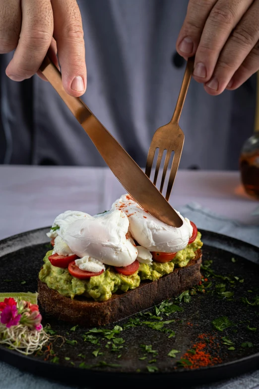 a person holding a knife and fork while  food onto small pieces