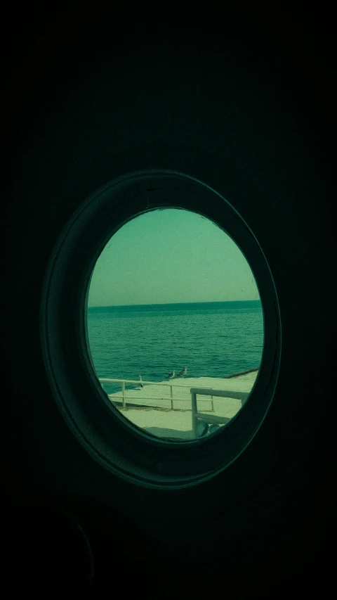 looking out the inside of a round window to sea