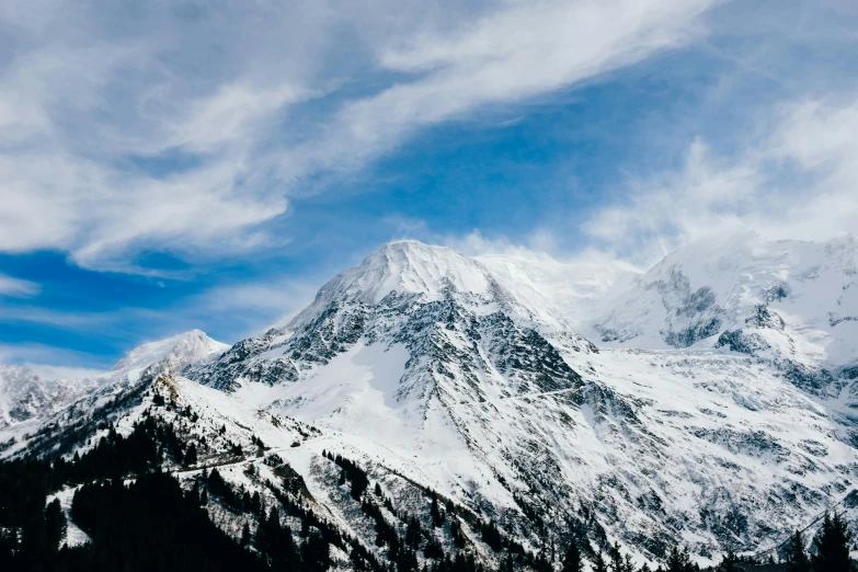 mountains with snow on them under a blue cloudy sky