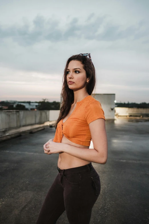 a beautiful young woman in an orange top posing for a po