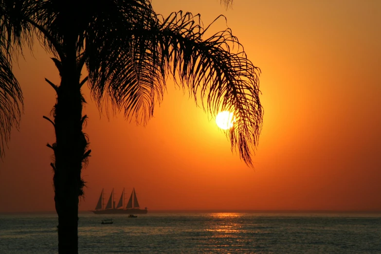 the sun setting over a tropical sea with boats on it