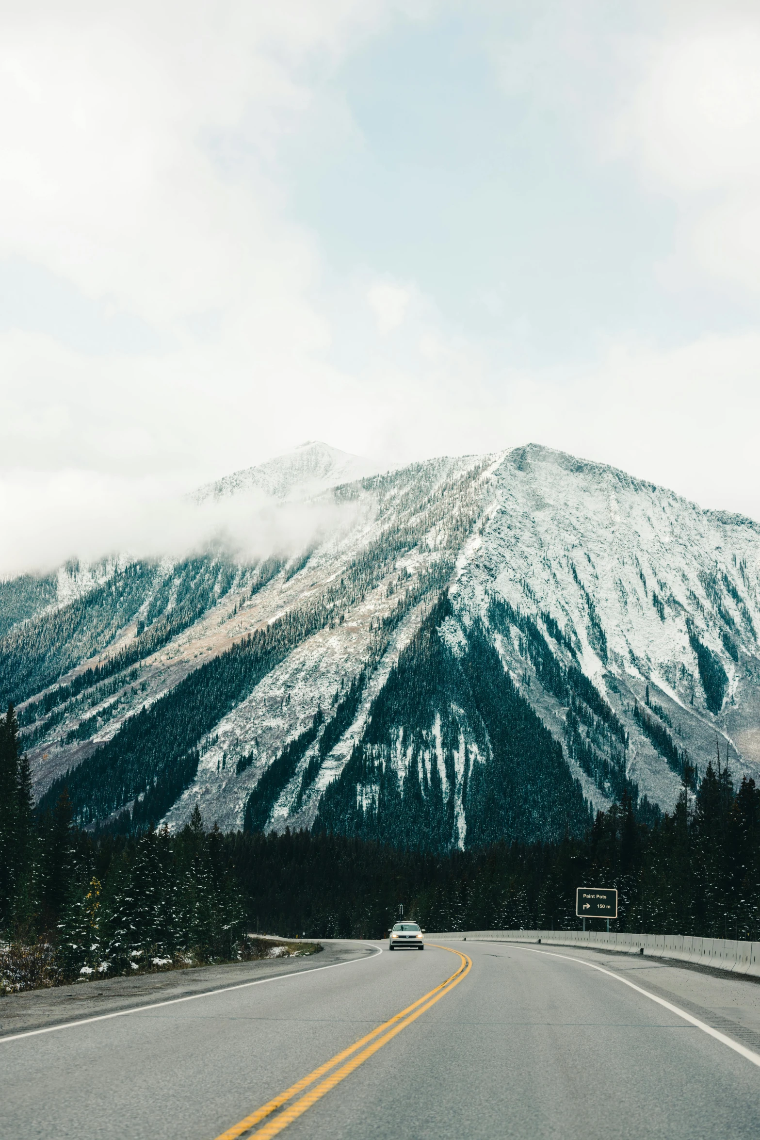 a road leads into a mountain range under clouds