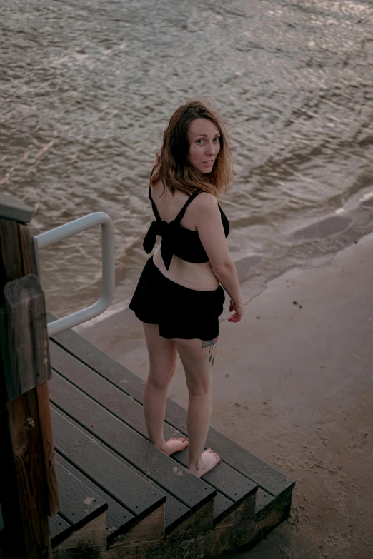 a girl standing on the dock at the beach