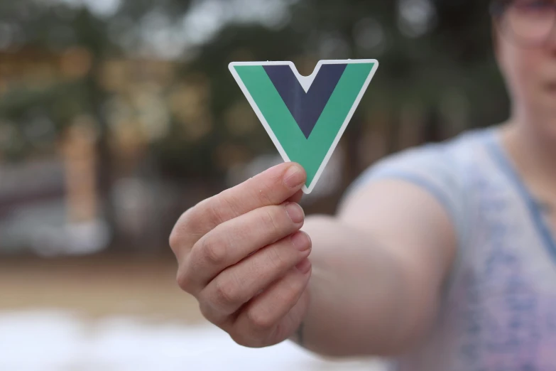 a hand holding a triangle sticker with a woman in background