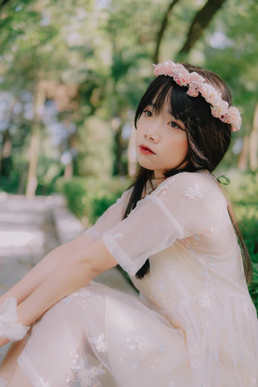 a beautiful young woman in white dress sitting on grass