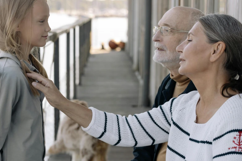 two older people stand on a dock and petting an older woman's tie