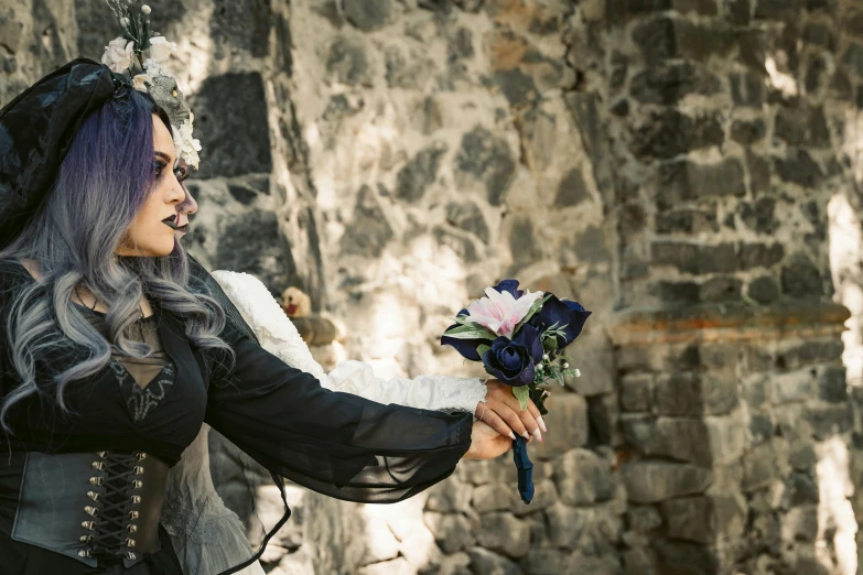 a person dressed in gothic clothing and holding a flower