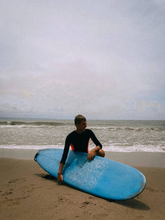 a surfer is sitting on the beach and waiting to ride the waves