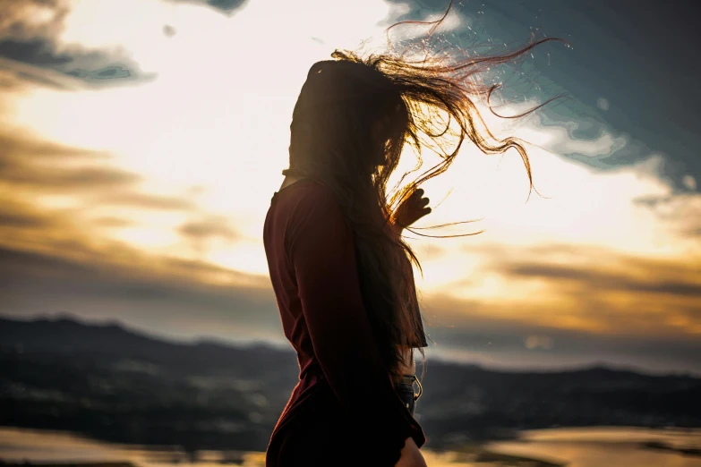 the woman's hair is in the wind over the water