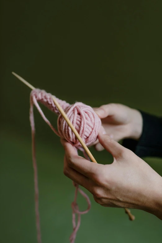 a person is holding a knitting needle and yarn