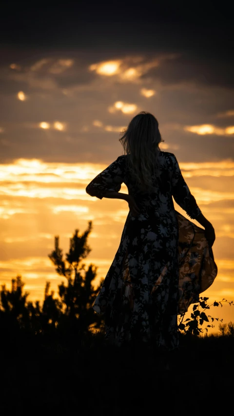 a woman holding a kite in her hand near the sunset