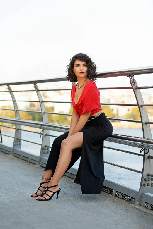 a woman sitting on a ledge in front of a lake