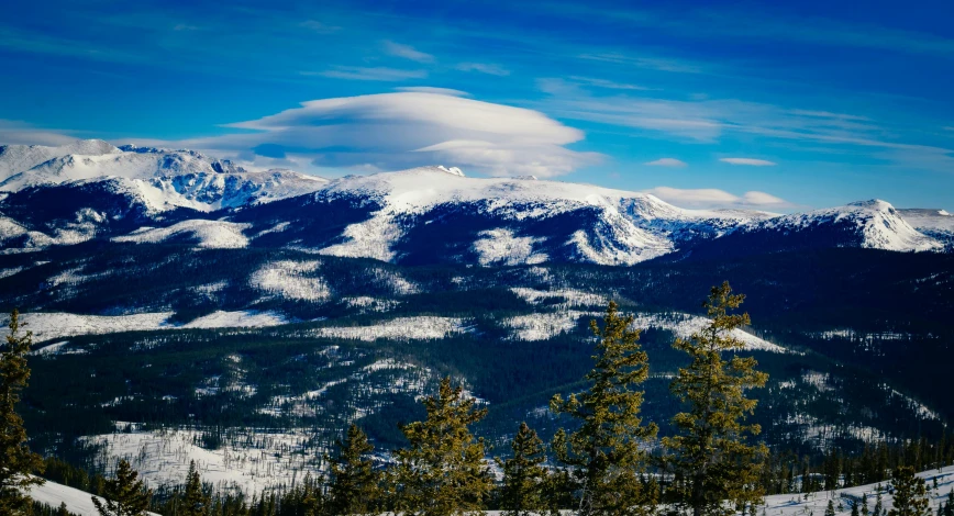 mountains are covered in snow and surrounded by trees