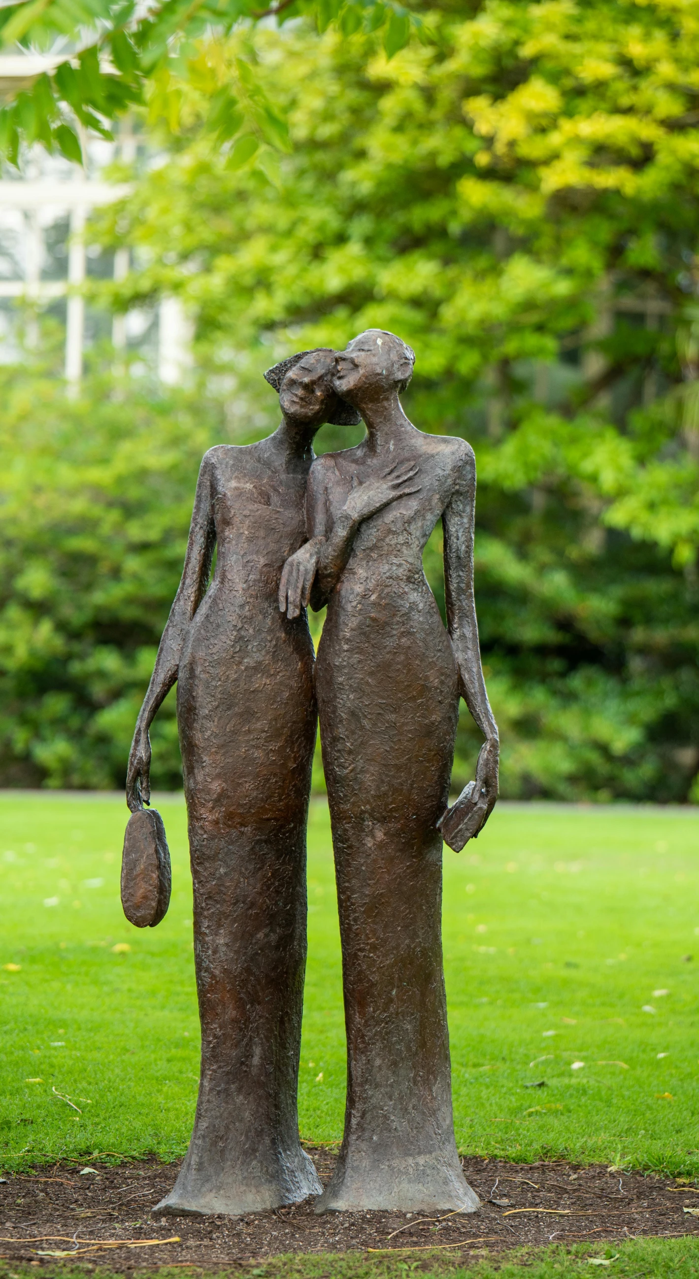 a statue stands next to a tree in a park