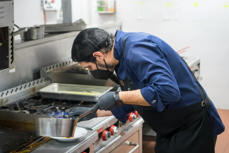 a man wearing gloves preparing food inside a restaurant kitchen