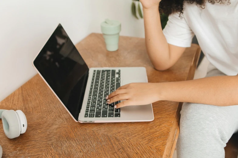 woman sitting at wooden table working on her laptop