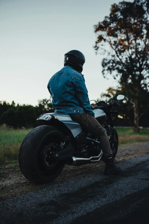 a man sitting on a parked motorcycle at the end of a road