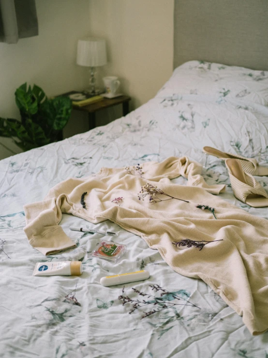 a blanket laying on a bed with tooth brushes and dental floss scattered on it