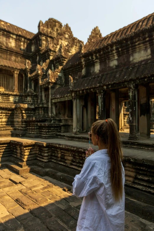 a girl standing next to the ruins of a castle