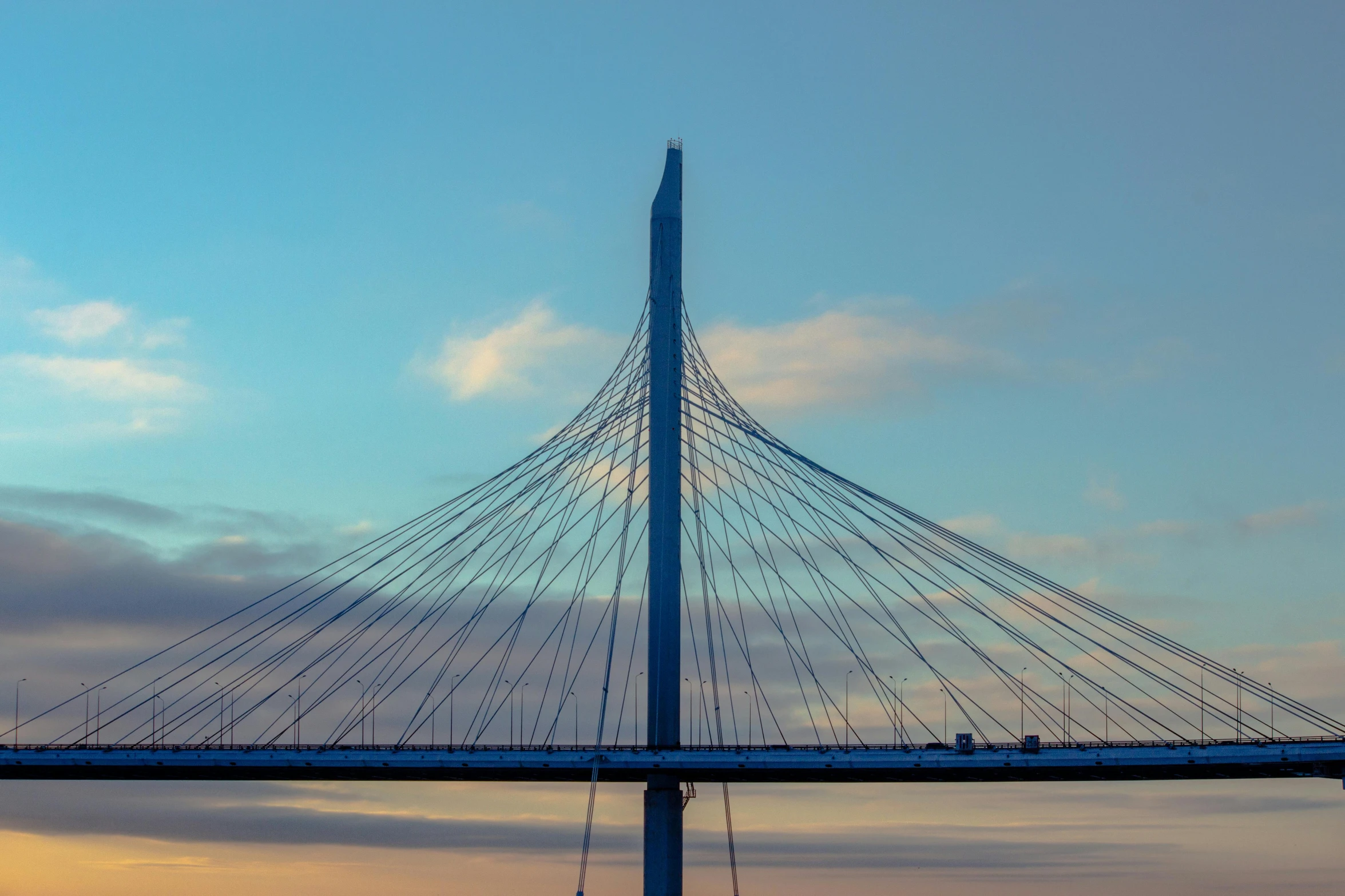 a long bridge with a blue top on it at sunset